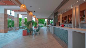 A spacious indoor area with a bar, seating, and potted plants.