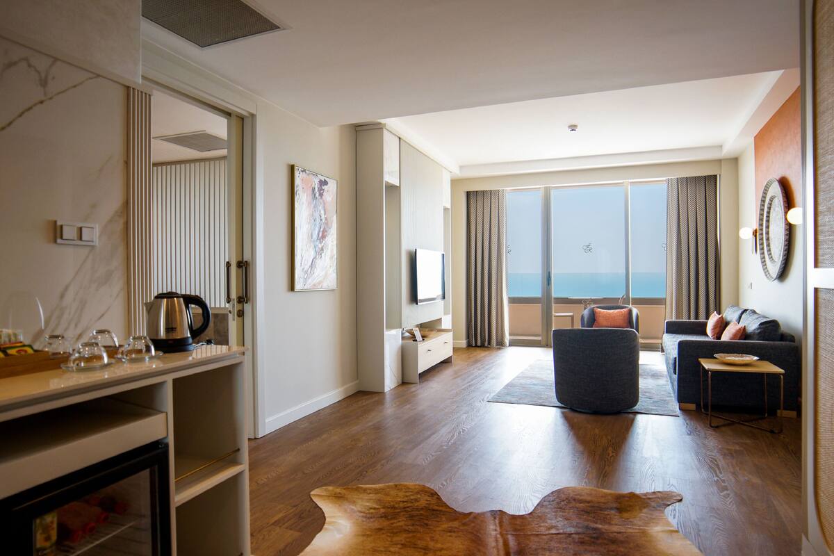 Uma sala de estar moderna com uma janela grande, um sofá, uma mesa de centro e um tapete de couro.