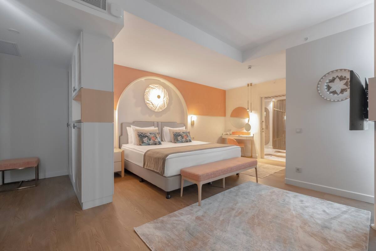 Quarto moderno com cama, banco e um espelho grande.