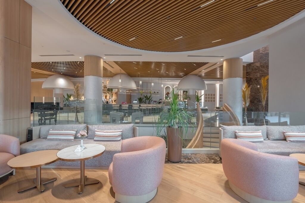 A modern lobby with a curved ceiling, seating areas, and a large plant.