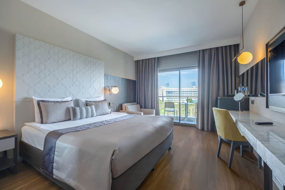Quarto de hotel moderno com uma cama grande, uma escrivaninha e vista para a cidade.