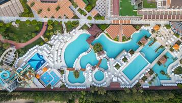 Luchtbeeld van een resort met diverse zwembaden, een waterpark en een tennisbaan.