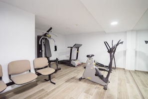 A fitness room with exercise equipment including a treadmill, elliptical, and weight machines. - Hotel Pozo del Duque (Barbate)