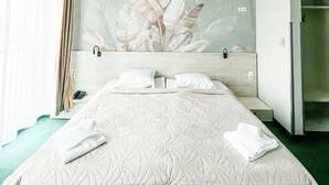 Ett hotellrum med en stor säng, en TV som är monterad på väggen och ett badrum med dusch.