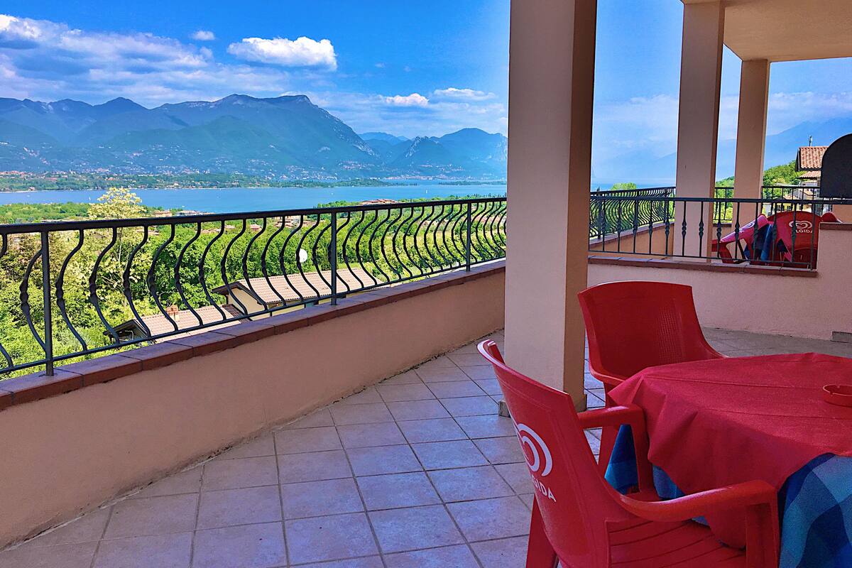 A balcony with a view of mountains and a lake.