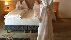 A bed with a canopy, wooden headboard, and a nightstand with a lamp. - AlpHotel Taller (Dimaro Folgarida)