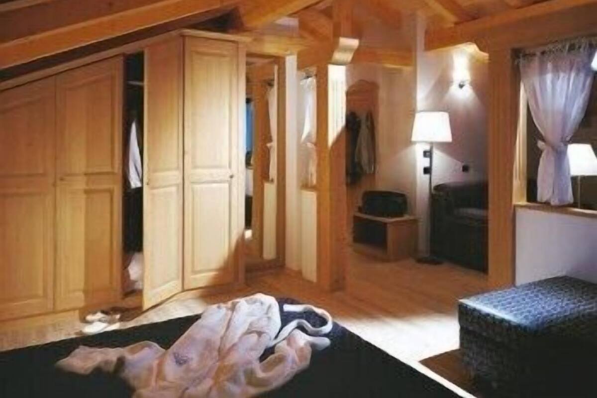 Et værelse i en træhytte med seng, stol, lampe og garderobeskab.