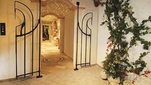 A hotel entrance with a decorative archway and a potted plant. - AlpHotel Taller (Dimaro Folgarida)