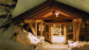 A wooden lodge with a snow-covered roof and a warm interior. - AlpHotel Taller (Dimaro Folgarida)