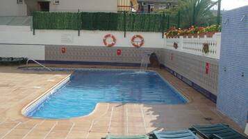 Een seizoensgebonden buitenzwembad en ligstoelen