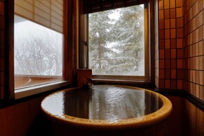 A wooden bathtub with a window above it, allowing a view of trees outside. - Takumi no Yado Miyama Ouan (Takayama)
