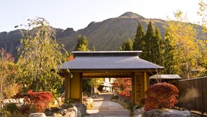 Un edificio tradicional japonés con tejado de cerámica, rodeado de rocas y árboles con follaje otoñal.