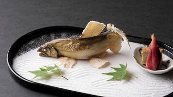 A dish with a fish, garnished with leaves and sugar, on a textured plate.