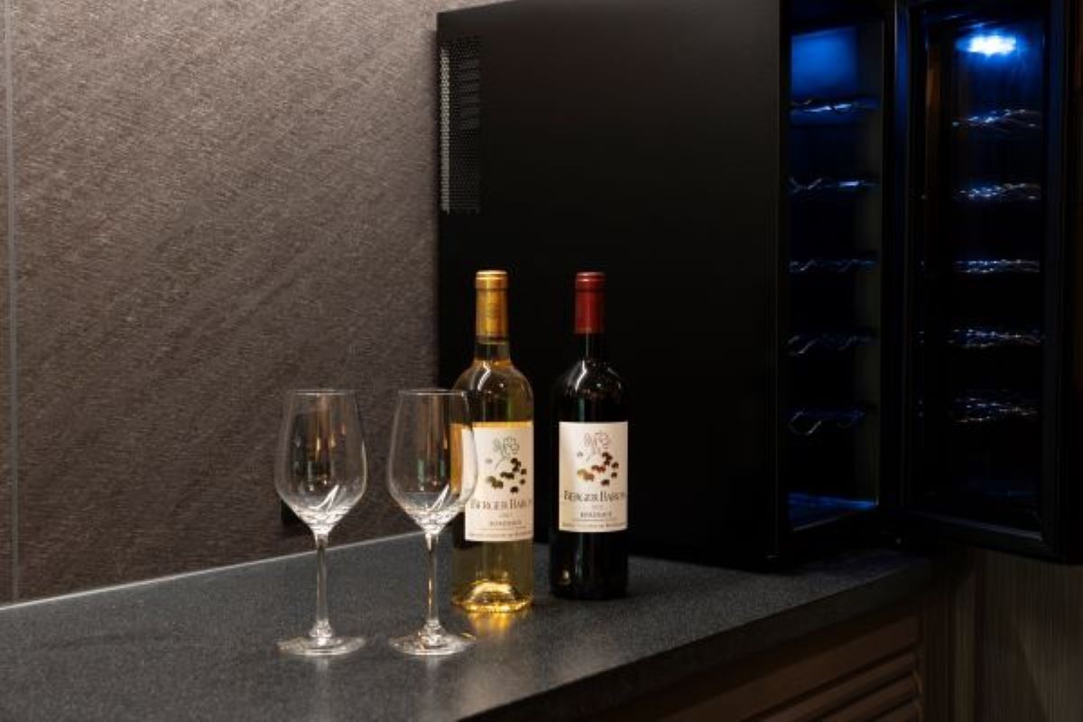 A wine bottle and two glasses on a countertop.