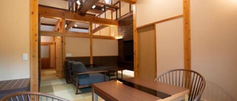 A room with a wooden ceiling, a table, two chairs, and a sofa.