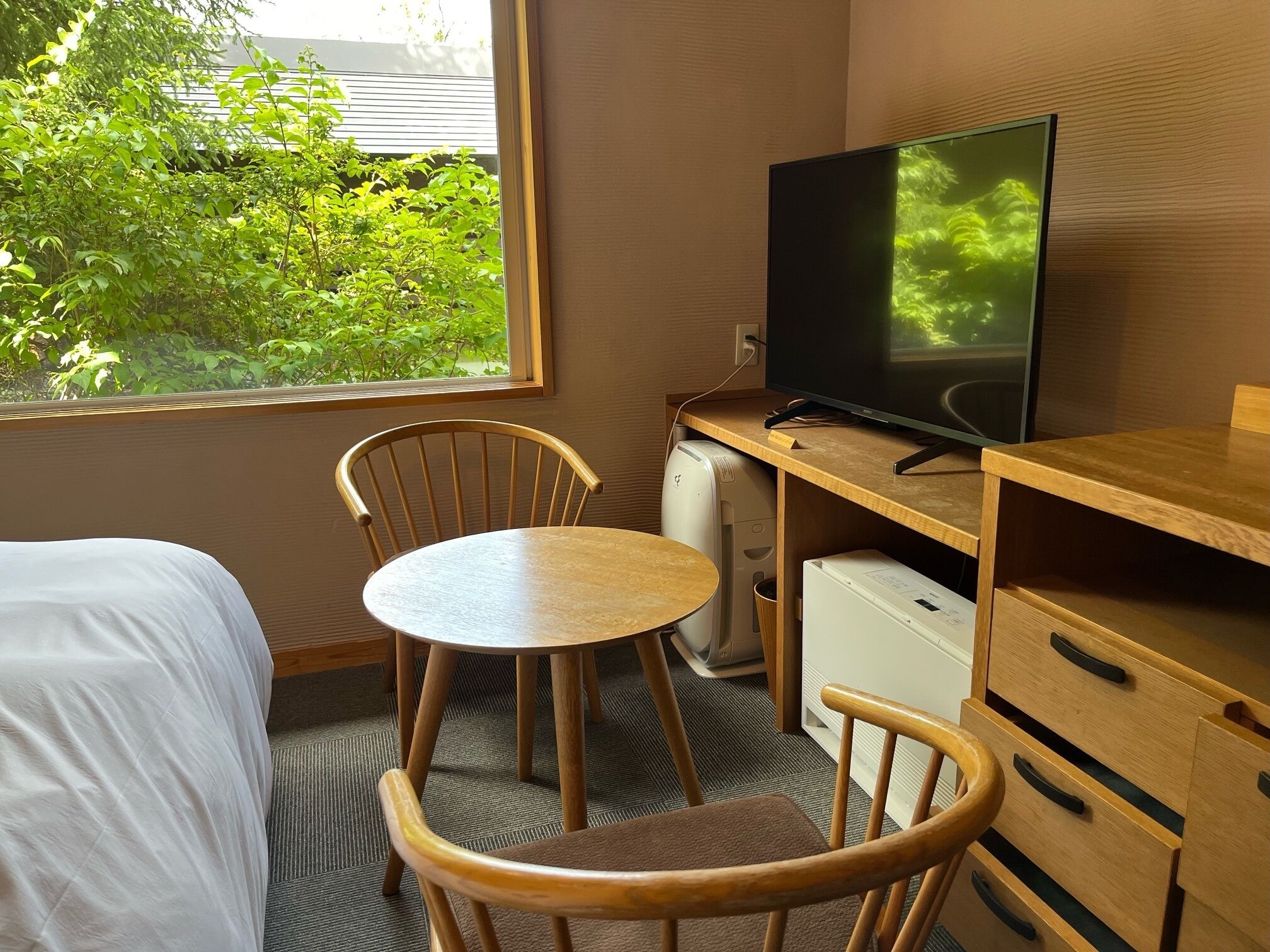 Une chambre d’hôtel comprenant un lit, un bureau avec une télévision, une chaise et un petit réfrigérateur.
