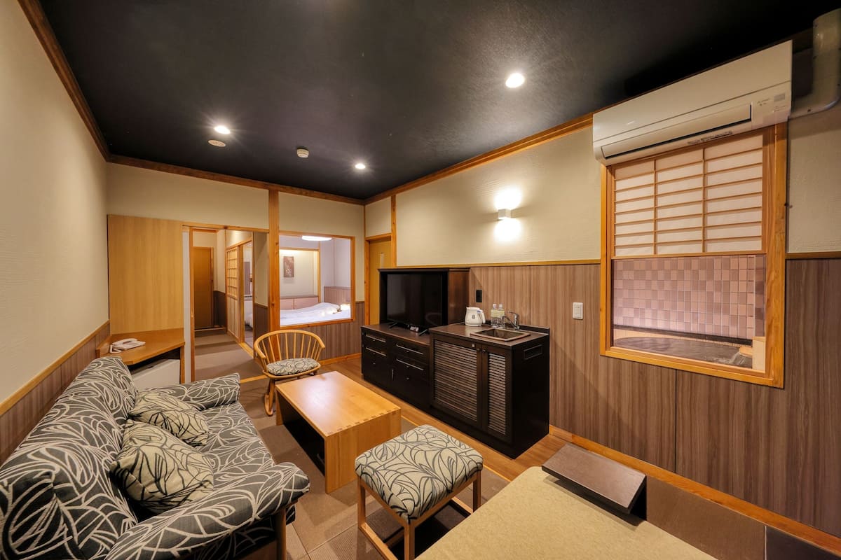 A compact living space with a sofa, a dining table, a TV, and a kitchenette.