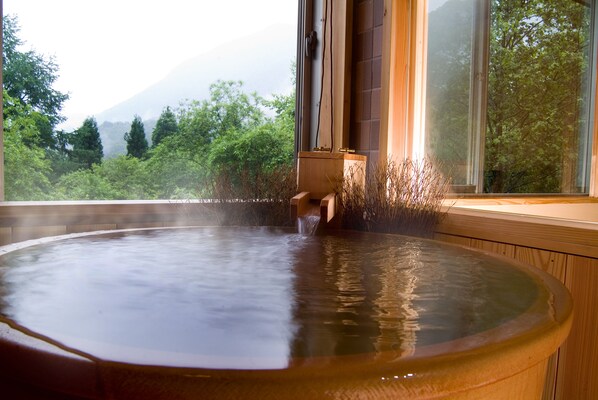 Un jacuzzi con vistas a un bosque y montañas a través de una ventana.