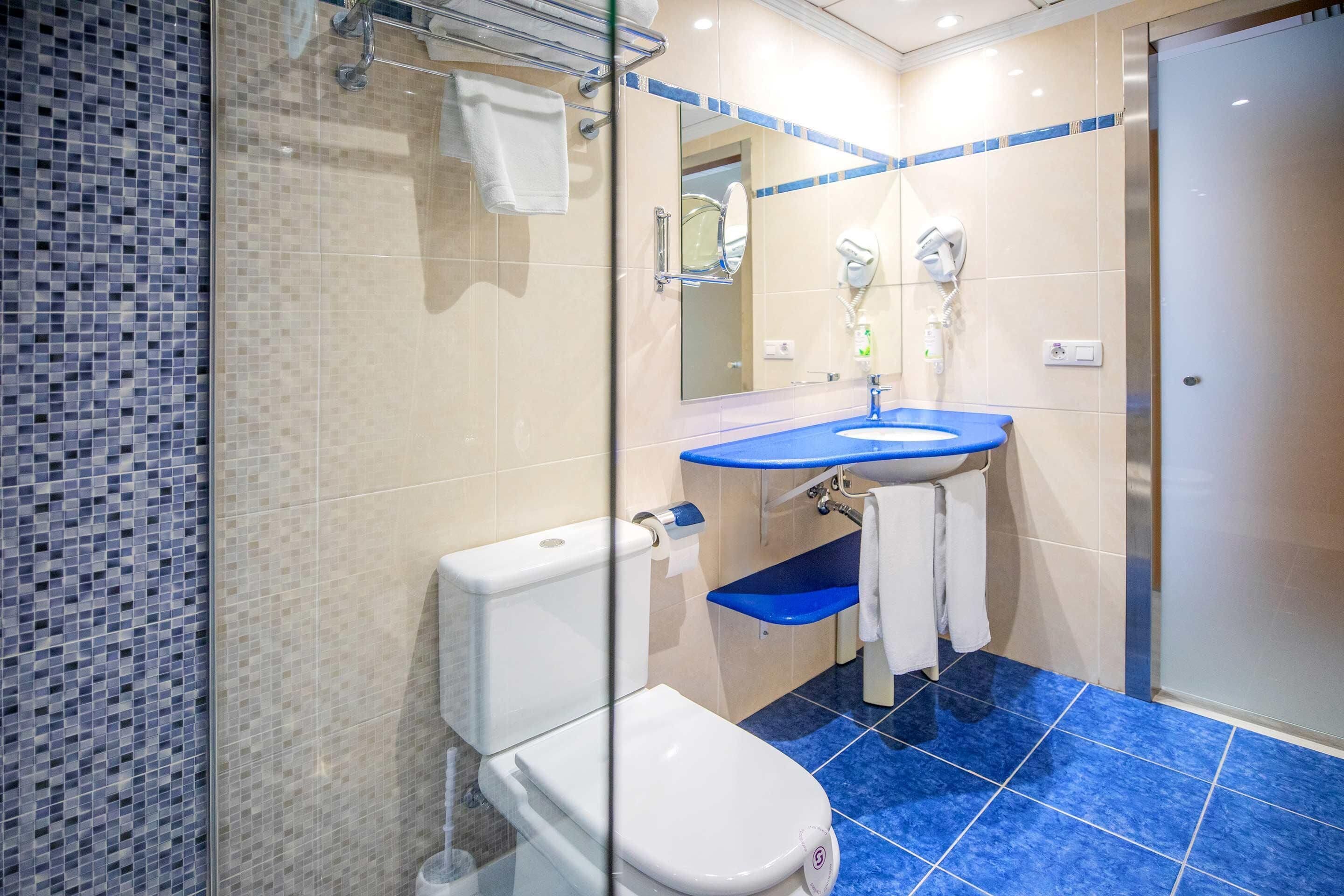 A bathroom with a toilet, sink, and shower area.