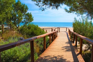 Un paseo marítimo de madera que conduce a una playa, con vista despejada al océano.