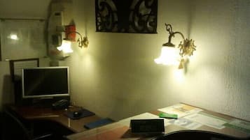 Habitación de hotel con escritorio, monitor de computadora, dos lámparas de pared y un adorno mural.