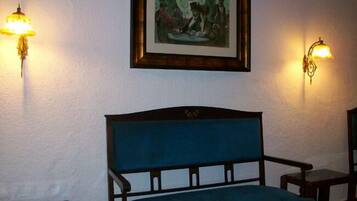 Una habitación con un sofá azul, una mesita con una lámpara y un cuadro en la pared.
