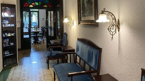 Ein Flur mit gemusterten Bodenfliesen, hölzernen Bänken und Wandleuchten.
