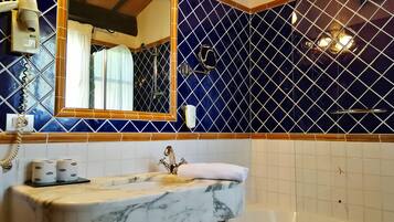 Une salle de bain avec un lavabo en marbre, un grand miroir et une baignoire.