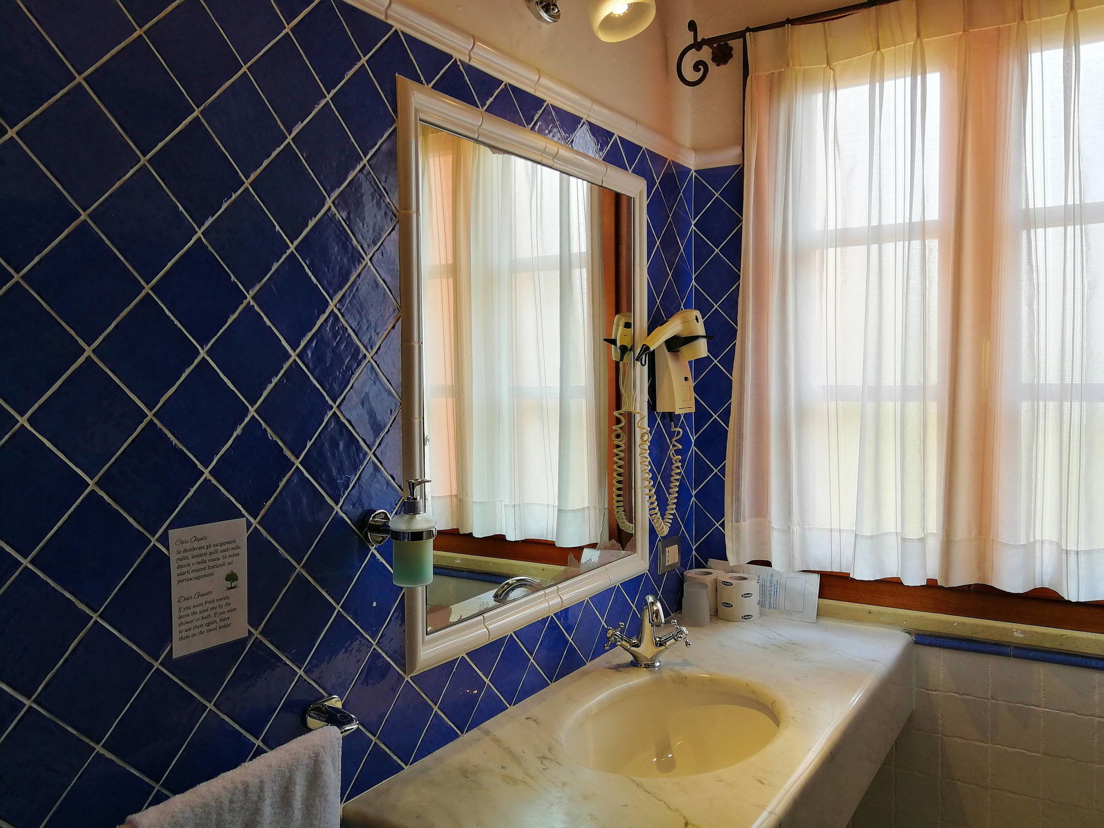 A bathroom with a sink, mirror, and blue tiled walls.
