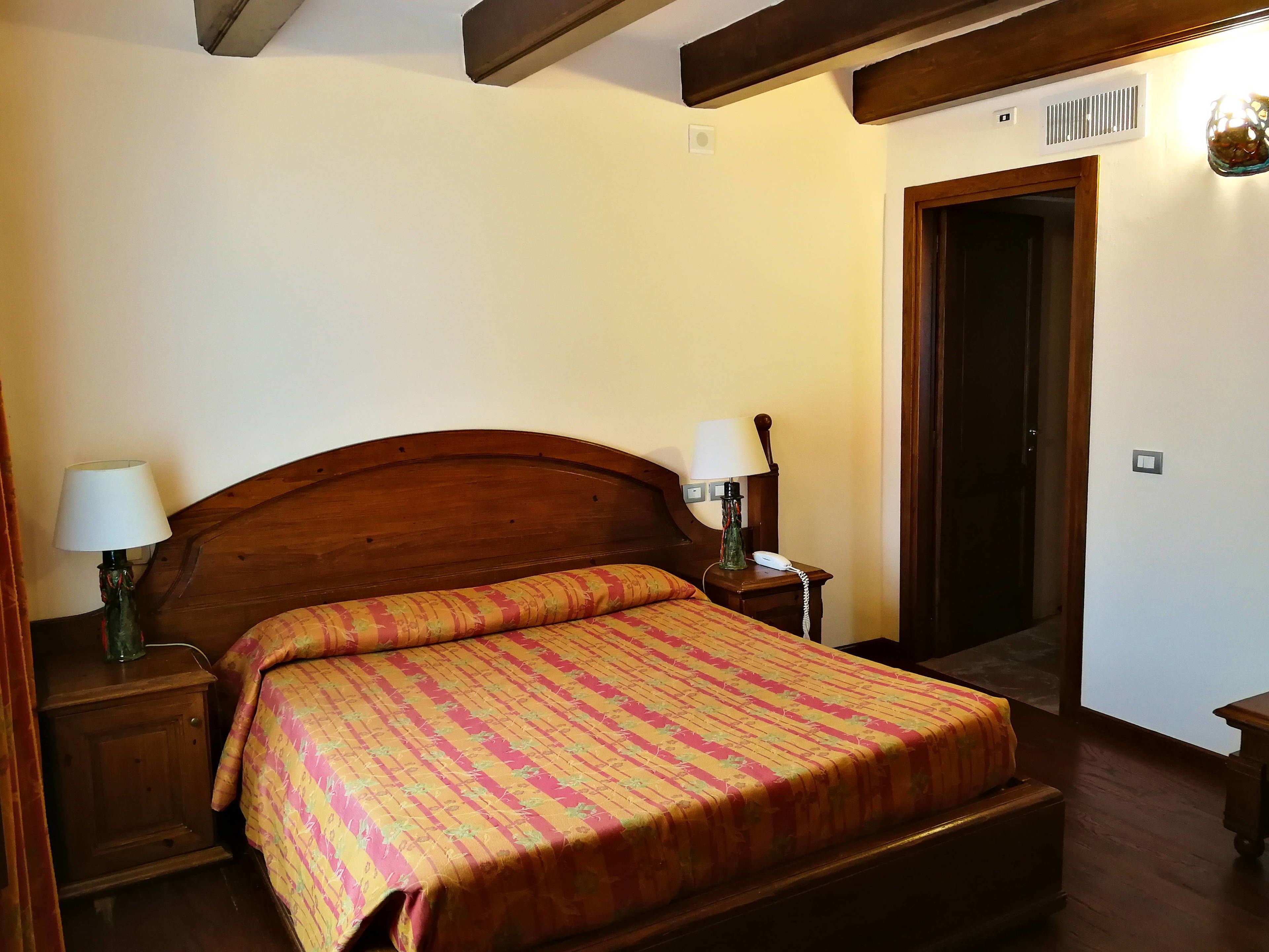A bedroom with a wooden bed, two bedside lamps, a nightstand, and a door.