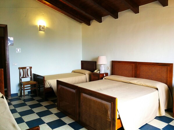 A hotel room with two single beds, a wooden chair, a desk, and a lamp.