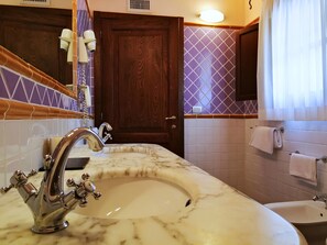 A bathroom with a marble sink, a wooden door, and a mirror. - Hotel Il Vecchio Mulino (Tortoli)