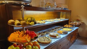 Un bufé con diversas frutas, bollería y postres.