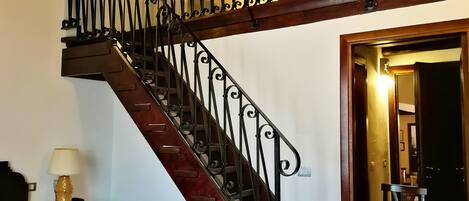 A staircase with ornate black railings and a wooden handrail, leading to an upper floor.