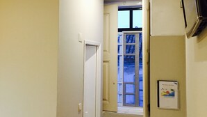 A narrow hallway with a door leading to a room, a window with a view, and a wall-mounted air conditioning unit. - Guest House São Filipe (Faro)