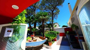 A hotel entrance with a sign reading "INGRESSO HOTEL GABBIANO," a blue boat, and potted plants. - Hotel Gabbiano (Manfredonia)