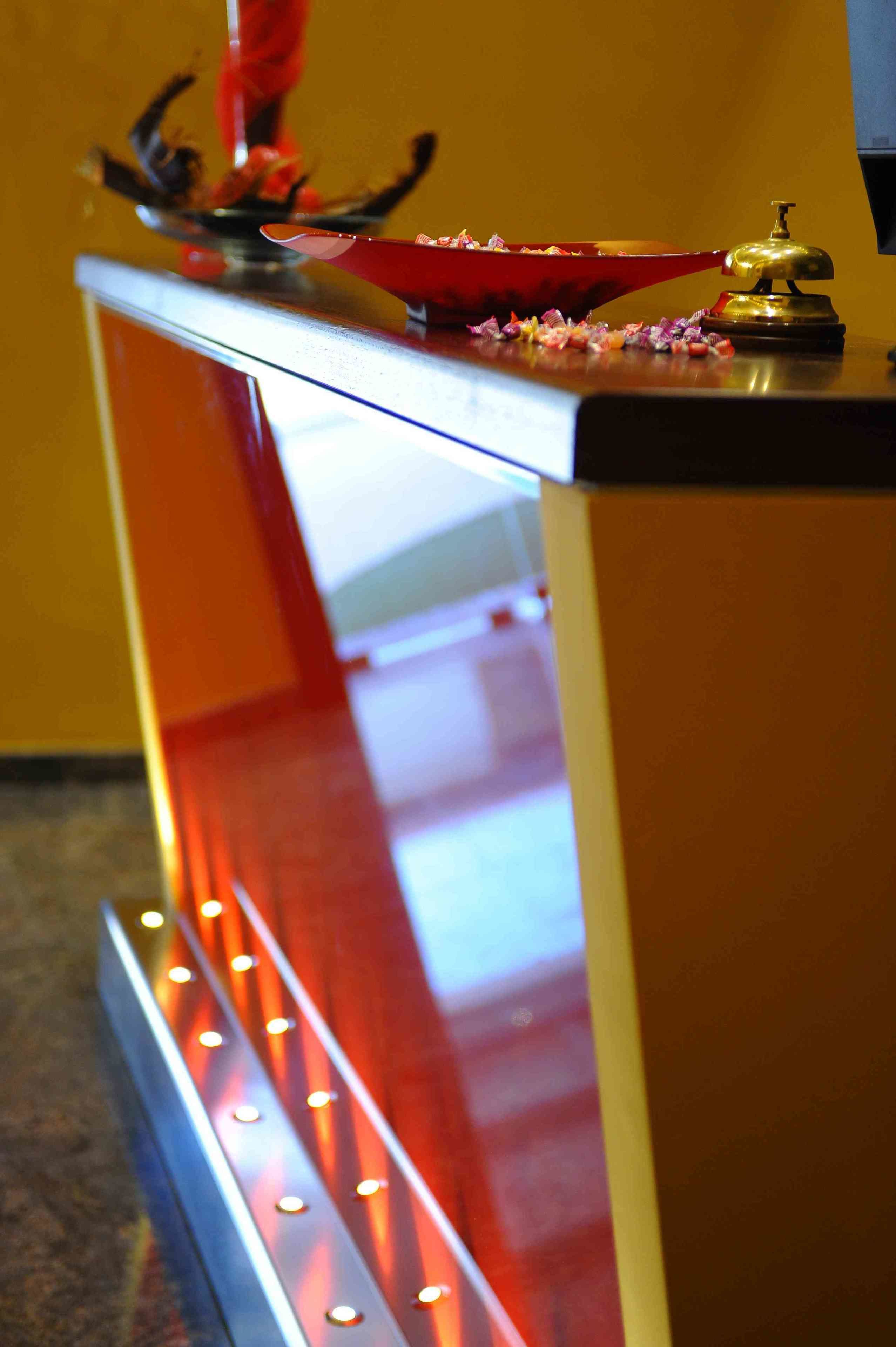 A reception desk with a red bowl, a bell, and a decorative item on top.