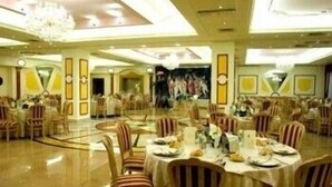 A spacious banquet hall with round tables and striped chairs, a chandelier, and a large painting on the wall. - Hotel Gabbiano (Manfredonia)