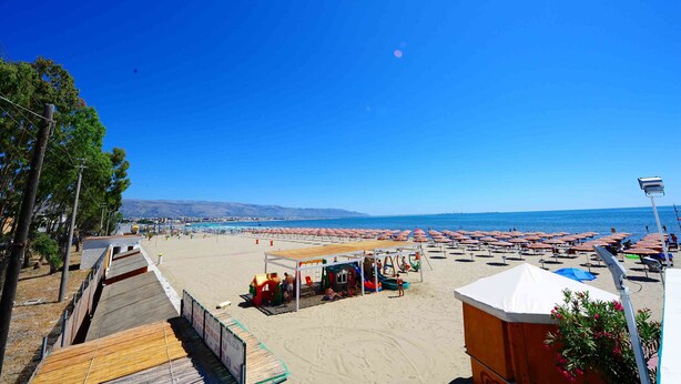A beach with umbrellas and a wooden deck. - Hotel Gabbiano (Manfredonia)