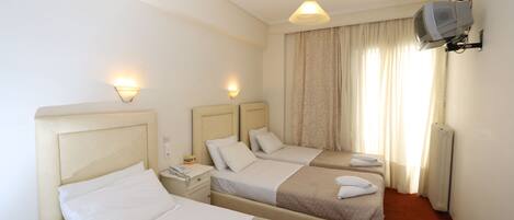 A hotel room with two beds, a TV mounted on the wall, and a ceiling light.