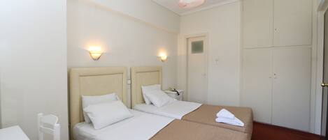 A hotel room with two beds, a desk, a chair, a wardrobe, and a bathroom.