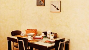 Un comedor con una mesa dispuesta para cuatro, sillas y algunos objetos decorativos.