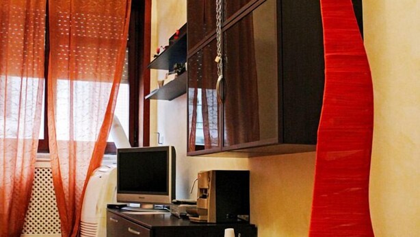 Una sala de estar con televisor de pantalla plana, un mueble y un adorno rojo.