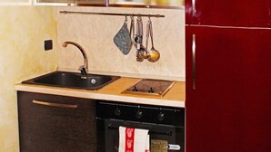 Una cocina compacta con muebles oscuros, un lavamanos de acero inoxidable y un horno empotrado.