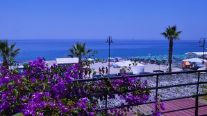 A beach with palm trees, umbrellas, and a clear blue sky. - Le Sirene Scilla (Scilla)