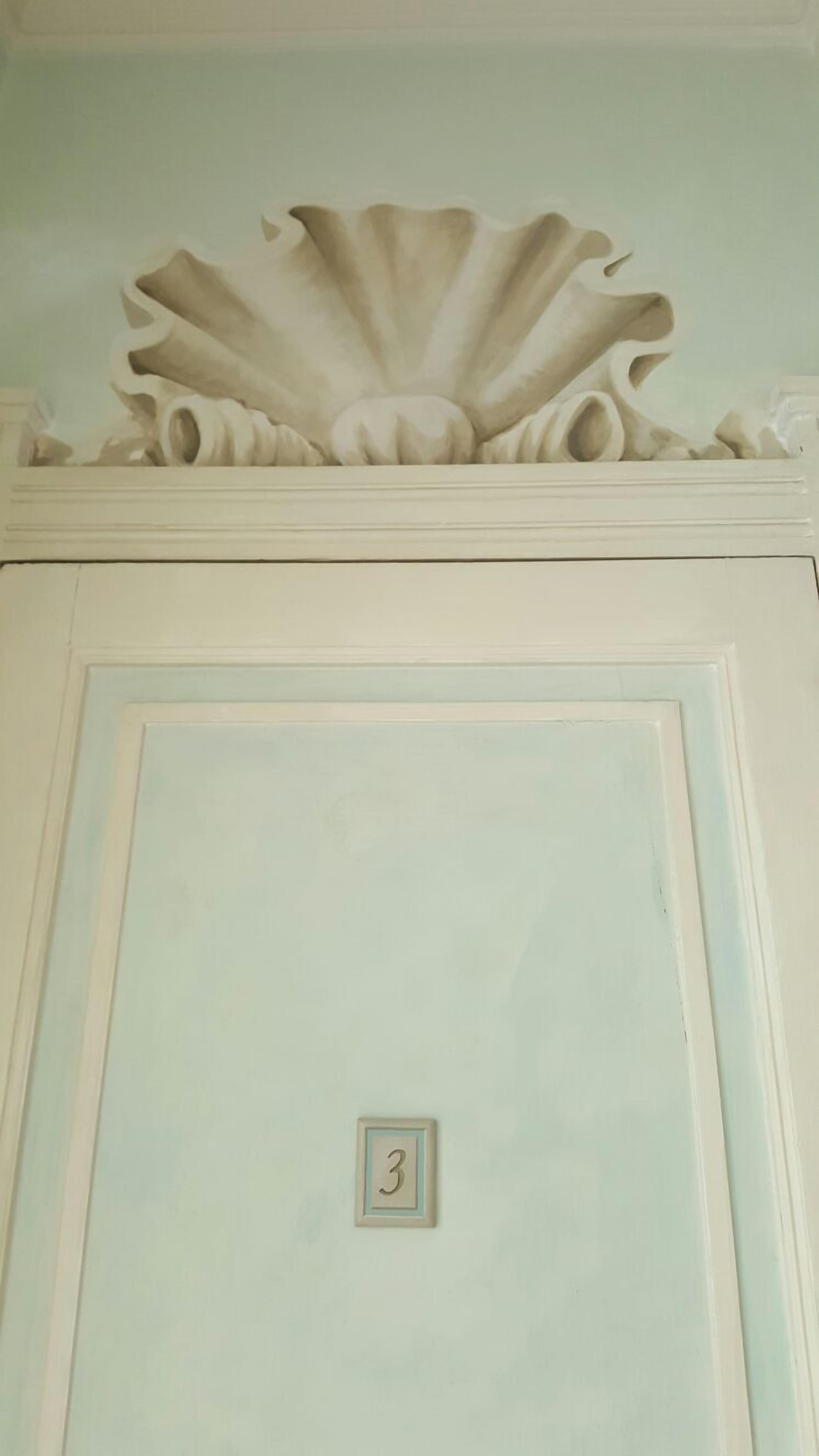 A door with a decorative molding and a small number plaque.