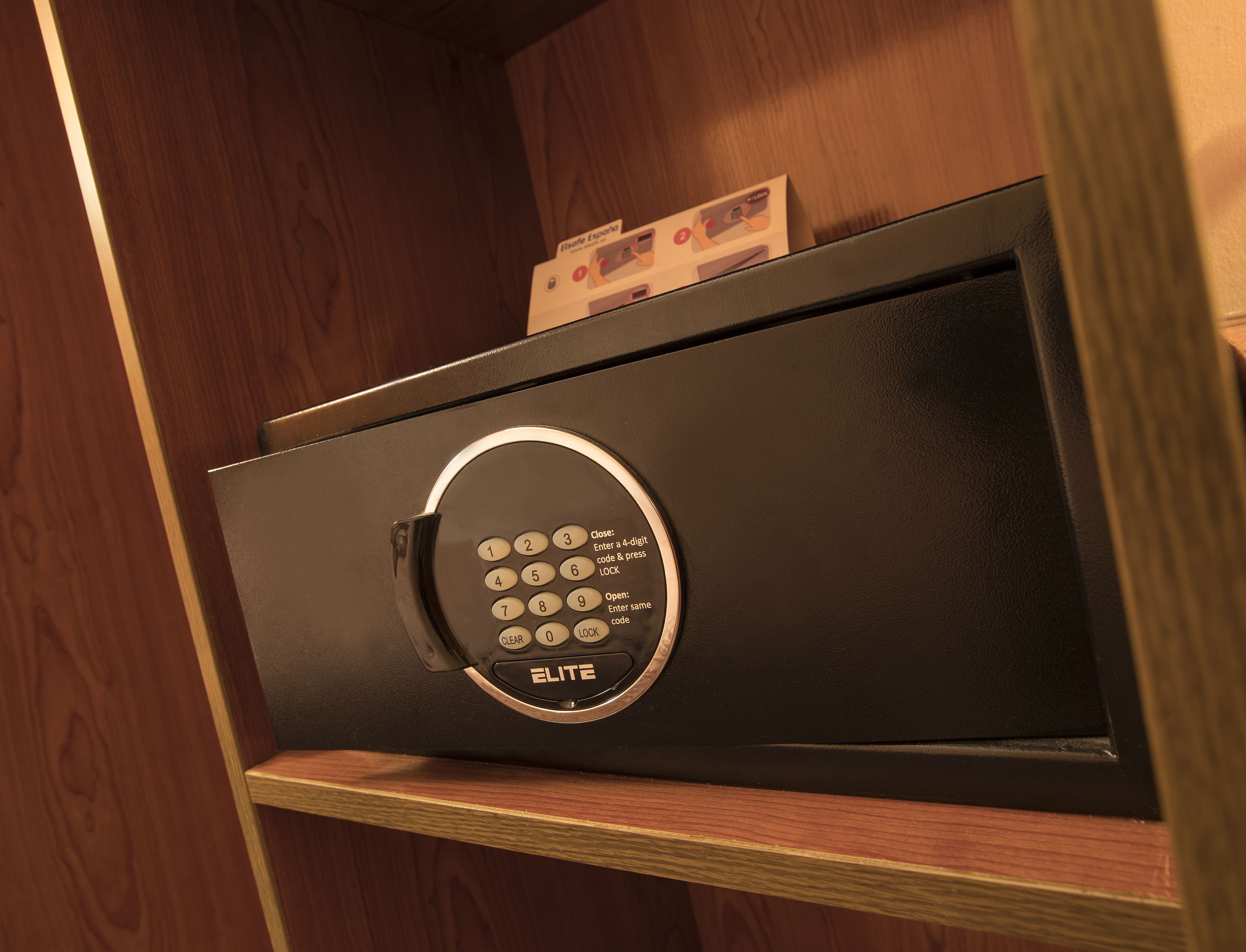 A black safe with a keypad, placed on a wooden shelf.