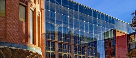 Un bâtiment moderne doté de grandes fenêtres en verre qui reflètent l’architecture environnante.