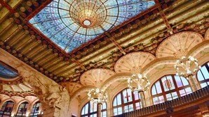 Interior ornamentado com uma grande cúpula de vidro, várias varandas e detalhes arquitetônicos elaborados.