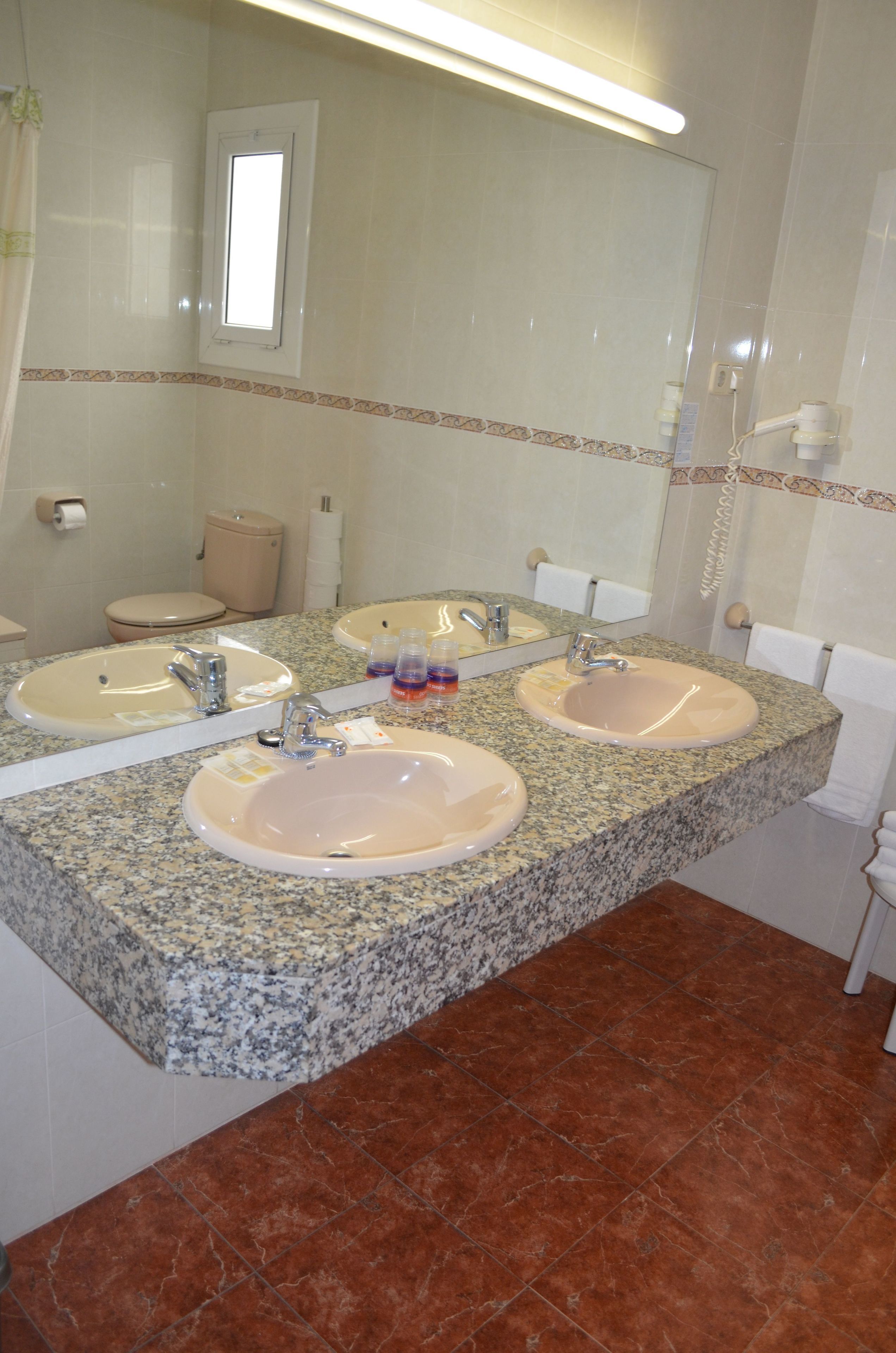 A bathroom with two sinks, a toilet, and a shower.